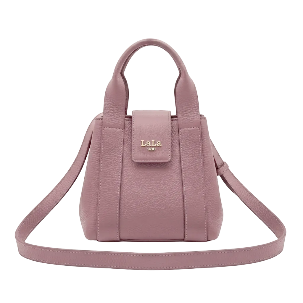 A dusty pink pebbled leather handbag with top handles and a detachable shoulder strap, featuring a gold-tone  logo on the front flap, set against a light gray background.